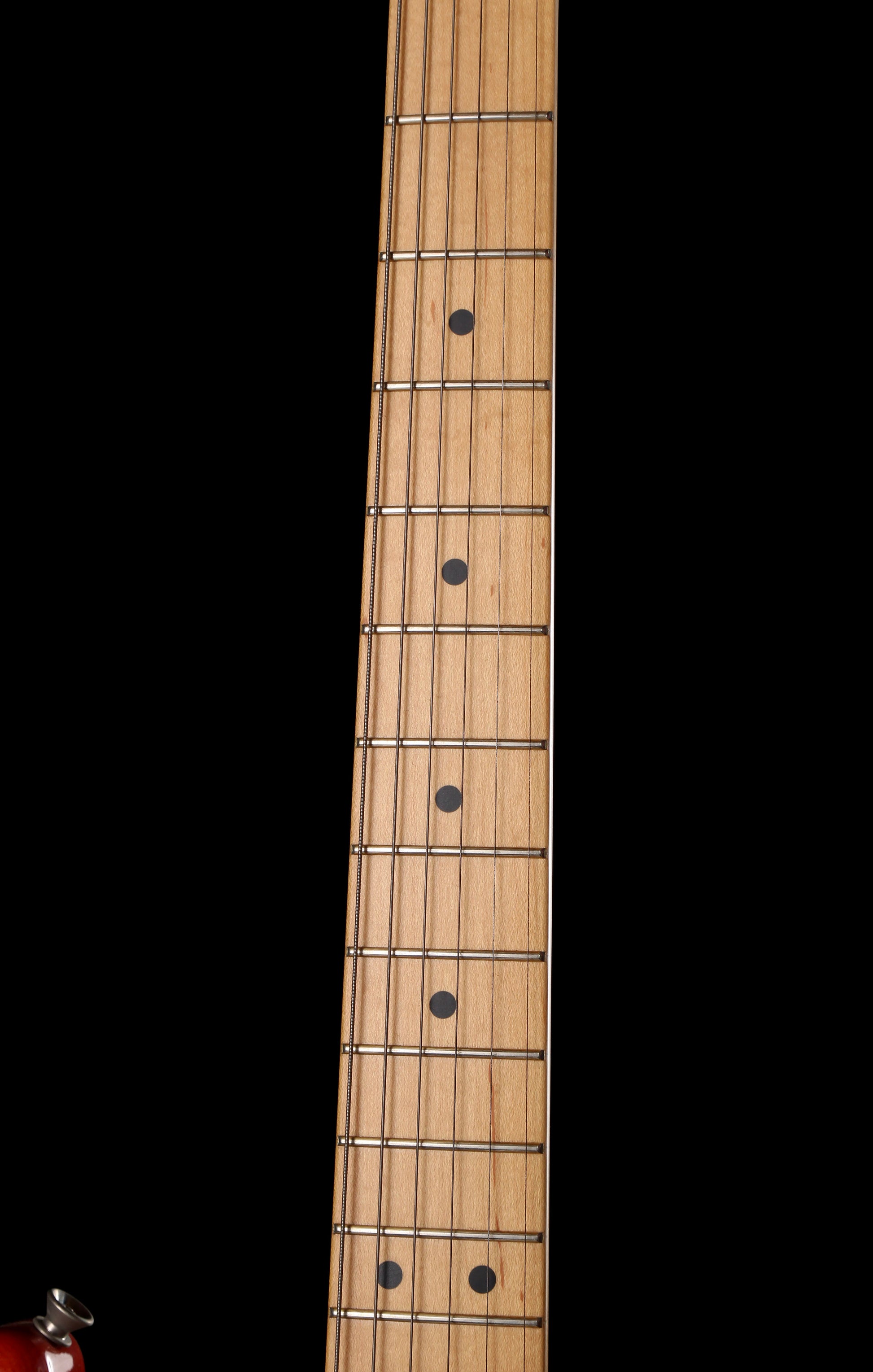 Fender Japan Michiya Haruhata Stratocaster Transparent Pink 2021: Close-up of a light natural wood guitar neck with six strings and black fretboard inlays against a solid black background.