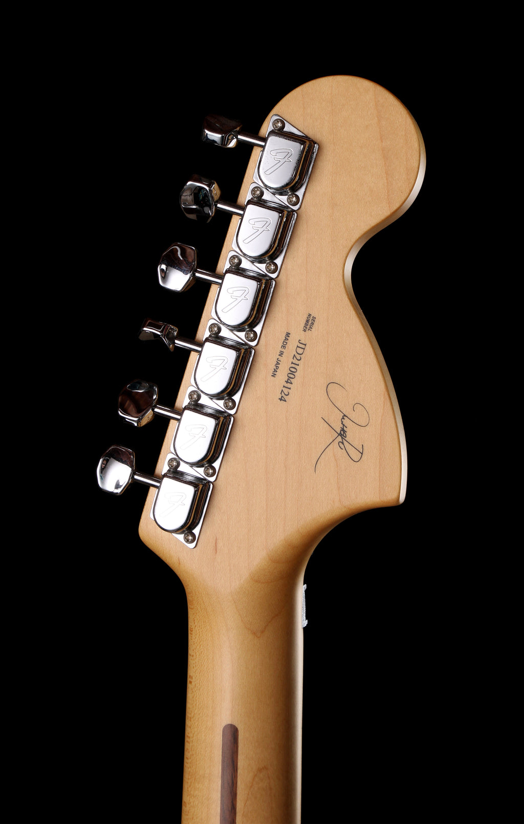 Fender Japan Michiya Haruhata Stratocaster Transparent Pink 2021: Close-up of the headstock of a Fender electric guitar in a natural maple finish, featuring six chrome tuning pegs and a black background.