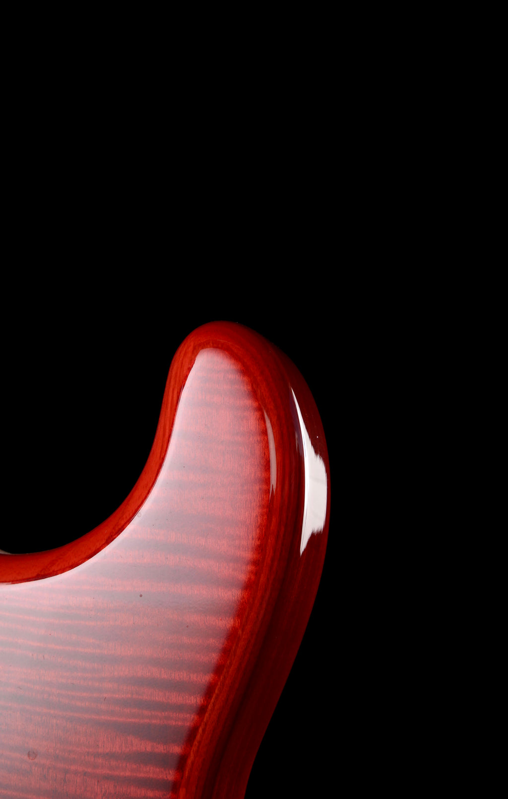 Fender Japan Michiya Haruhata Stratocaster Transparent Pink 2021: Close-up of a glossy red electric guitar body with a flamed wood grain finish against a solid black background.