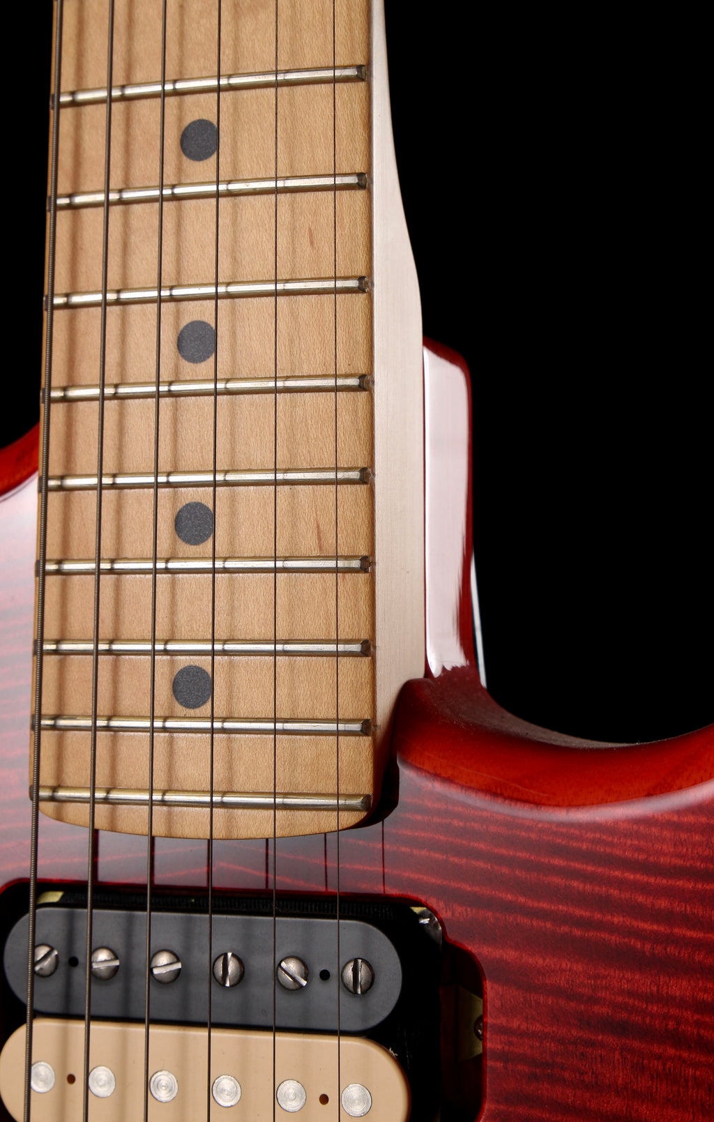 Fender Japan Michiya Haruhata Stratocaster Transparent Pink 2021: Close-up of a guitar's neck and body showing a maple fretboard with black dot inlays, six strings, a black pickup, and a glossy red cherry wood finish against a black background.