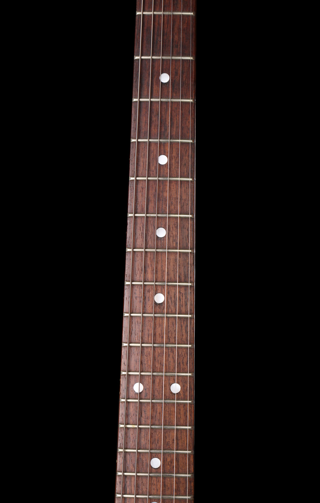 Fernandes EX Explorer Special Order SGS Sparkle Green Sunburst MIJ 1984: Close-up of a dark brown wooden guitar neck with white dot inlays on a solid black background.