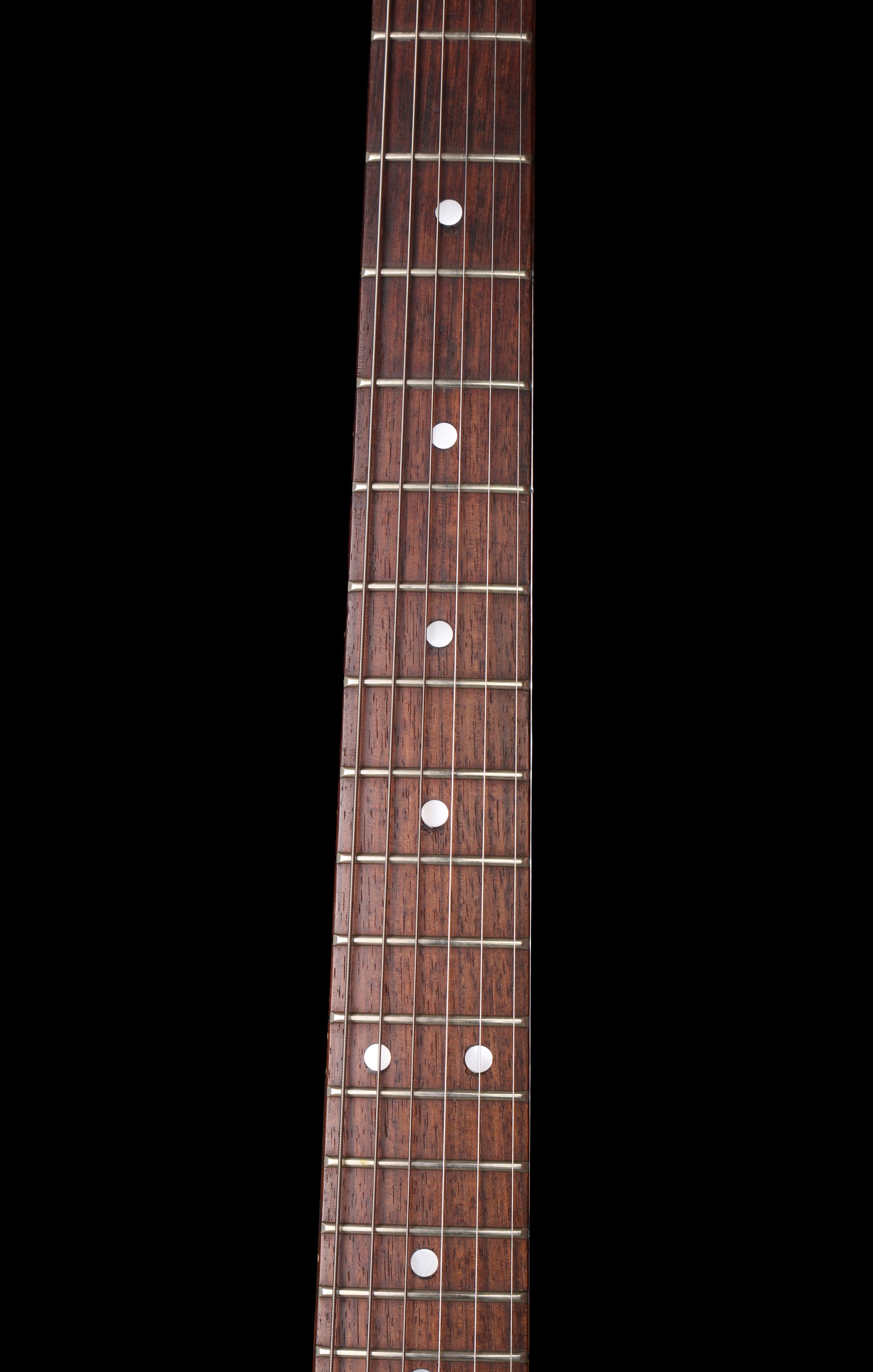 Fernandes EX Explorer Special Order SGS Sparkle Green Sunburst MIJ 1984: Close-up of a dark brown wooden guitar neck with white dot inlays on a solid black background.