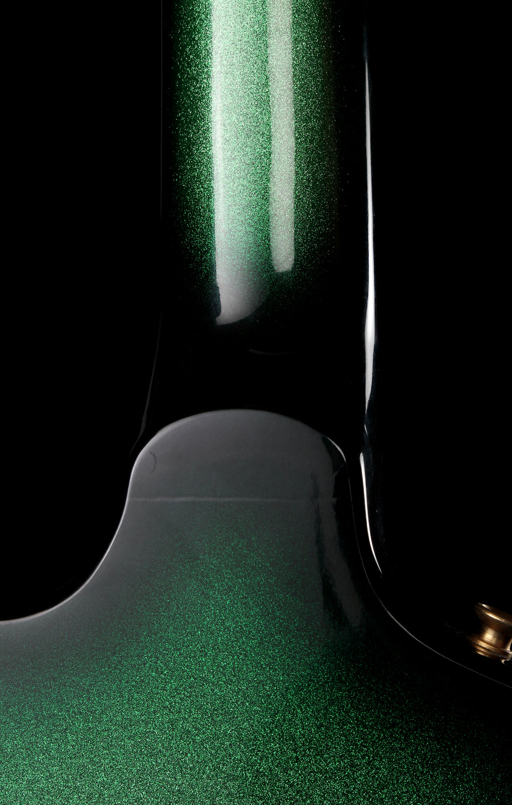 Fernandes EX Explorer Special Order SGS Sparkle Green Sunburst MIJ 1984: Close-up of a glossy green electric guitar body with a metallic glitter finish, showing the edge of the neck and a small gold tuning peg against a black background.
