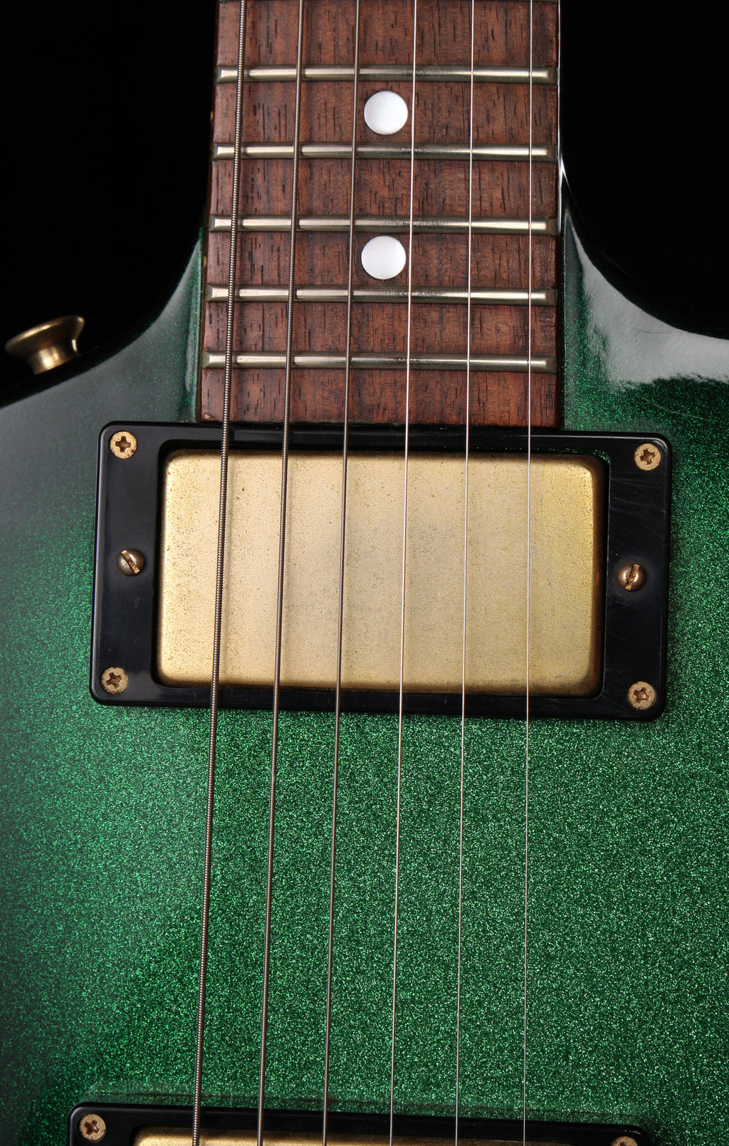 Fernandes EX Explorer Special Order SGS Sparkle Green Sunburst MIJ 1984: Close-up of a green electric guitar body with a gold humbucker pickup and dark wood fretboard against a black background.