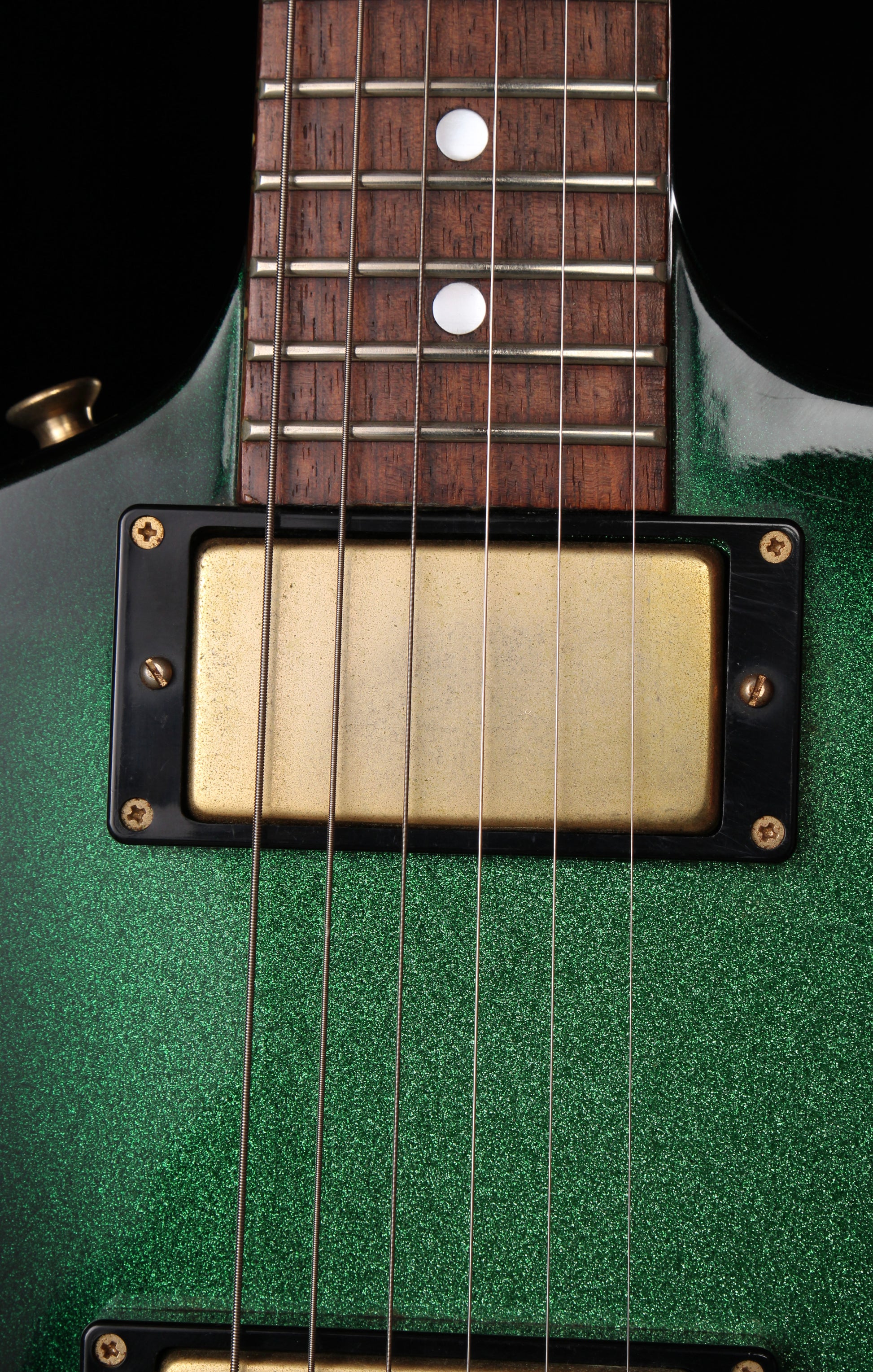 Fernandes EX Explorer Special Order SGS Sparkle Green Sunburst MIJ 1984: Close-up of a green electric guitar body with a gold humbucker pickup and dark wood fretboard against a black background.
