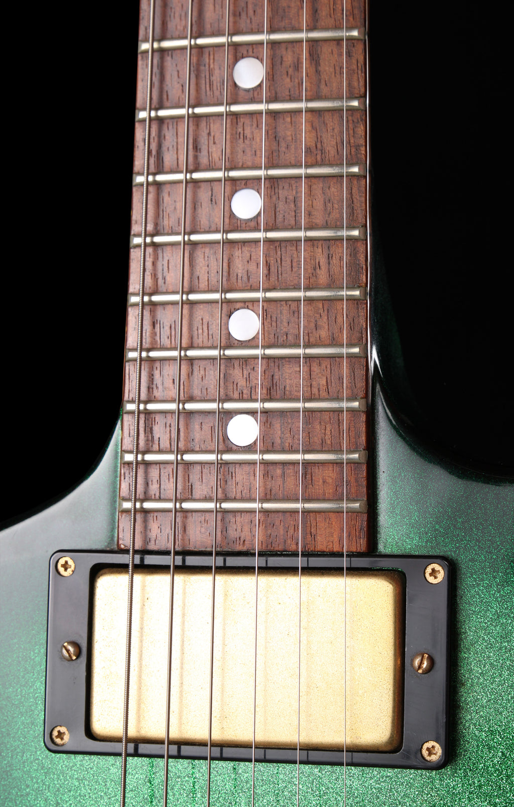 Fernandes EX Explorer Special Order SGS Sparkle Green Sunburst MIJ 1984: Close-up of a green electric guitar body and dark wood fretboard with silver metal frets and a cream-colored humbucker pickup.