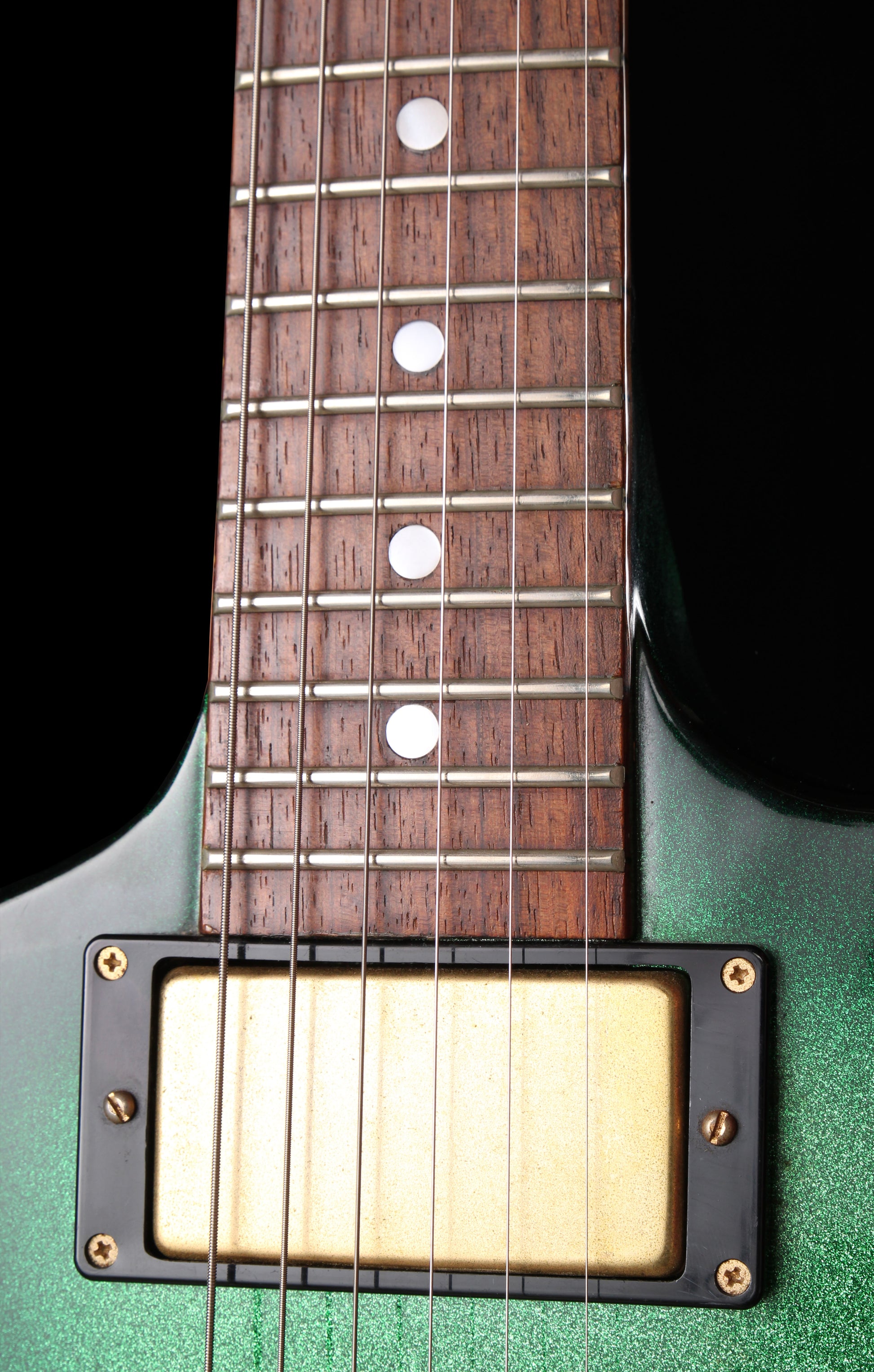 Fernandes EX Explorer Special Order SGS Sparkle Green Sunburst MIJ 1984: Close-up of a green electric guitar body and dark wood fretboard with silver metal frets and a cream-colored humbucker pickup.