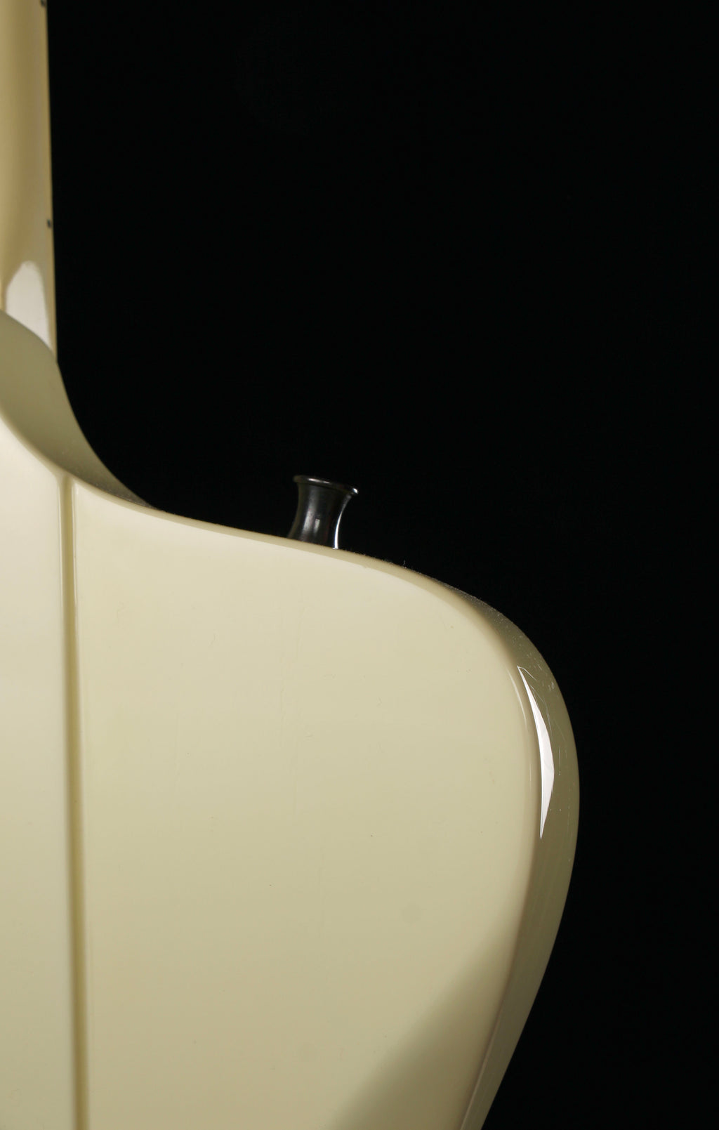 Fernandes FGJ-85RC Robbin Crosby Signature Firebird White 1986: Close-up of a glossy cream-colored guitar body corner against a solid black background.